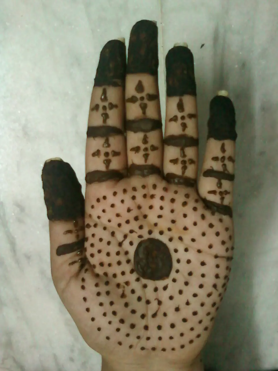 Diseño de henna con tono oscuro sobre la mano
