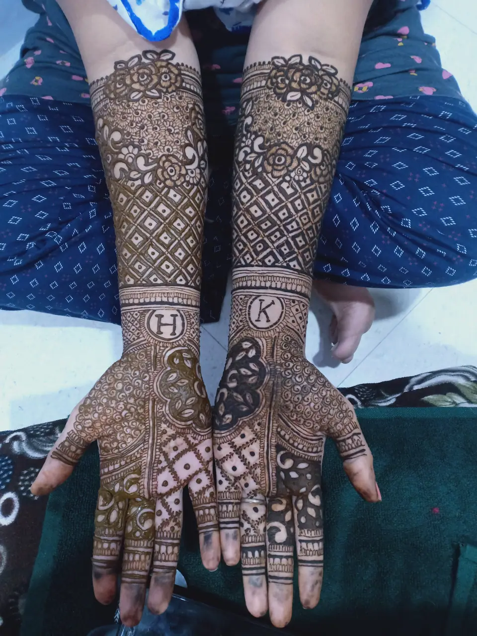 Manos con henna mostrando iniciales, diseño temporal