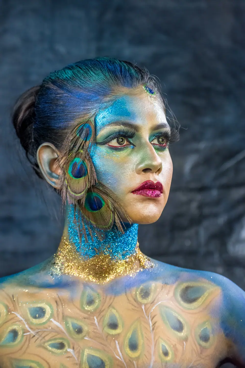Maquillaje corporal con motivo de plumas de pavo real sobre cuello y hombros