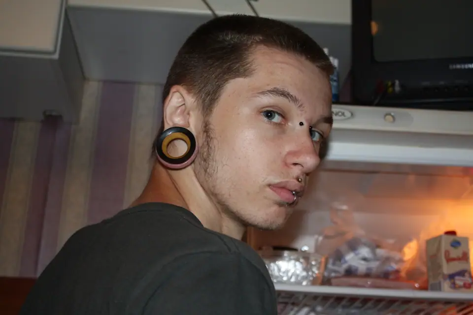 Joven con piercing bridge en el puente de la nariz, entre los ojos, además de medusa y labret en el labio y un túnel en la oreja
