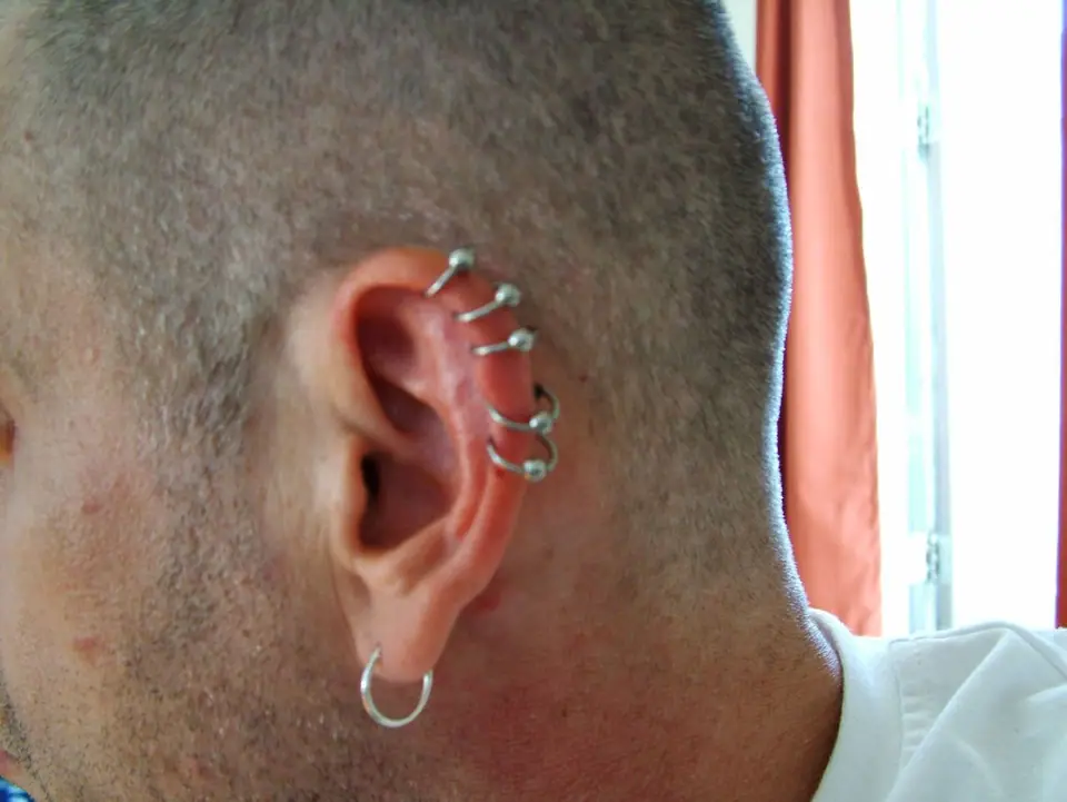 Varios piercings de cartílago (helix) a lo largo del borde de la oreja