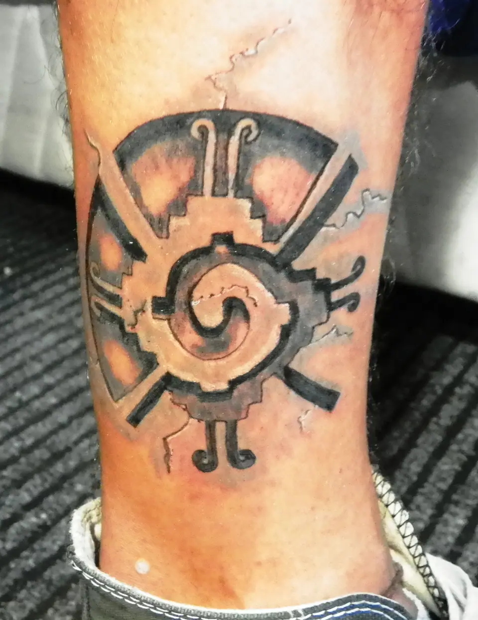 Tatuaje de un glifo de estilo azteca en el tobillo
