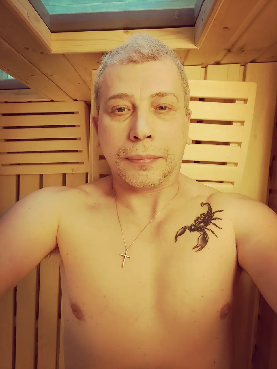 Tatuaje de un escorpión en el pecho, junto a un collar con una cruz