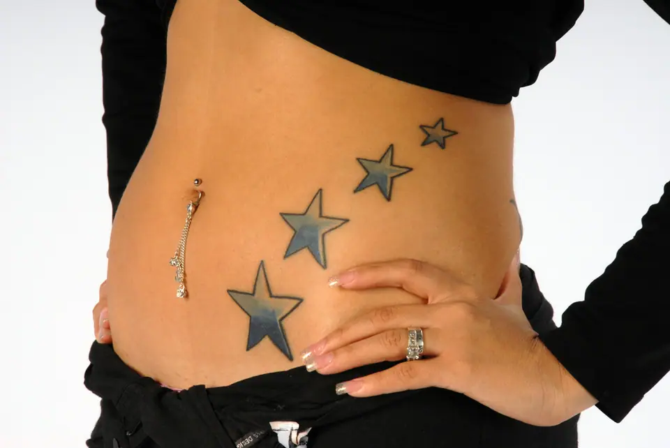 Tatuajes de estrellas en tamaño decreciente formando un rastro en el costado del abdomen