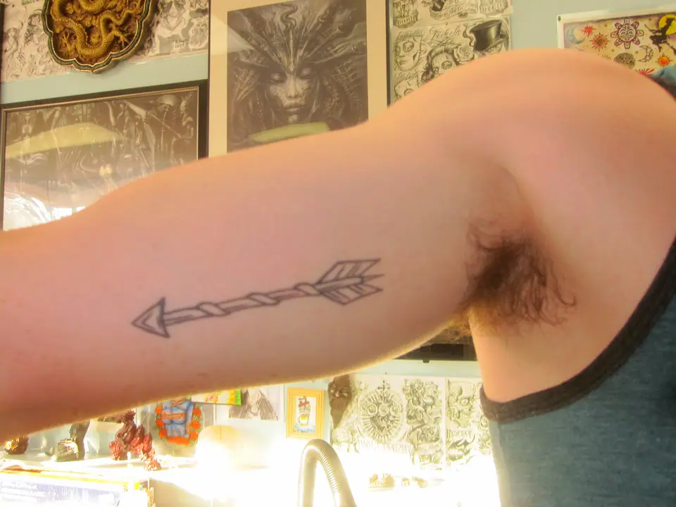 Tatuaje lineal de una flecha en la cara interna del antebrazo