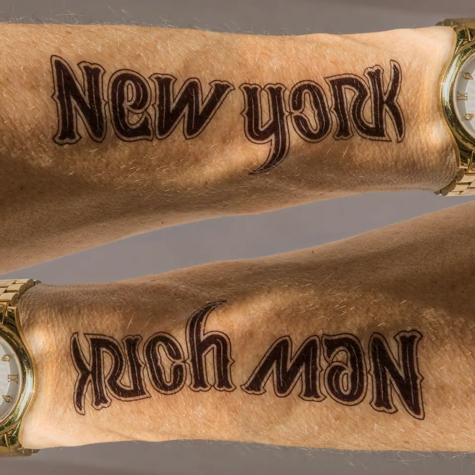 Tatuaje de lettering ambigrama New York / Rich Man en el antebrazo