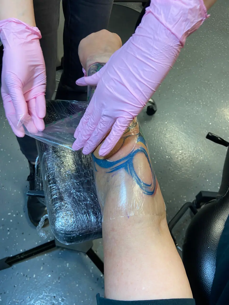 Tatuador cubriendo un tatuaje recién hecho con film plástico