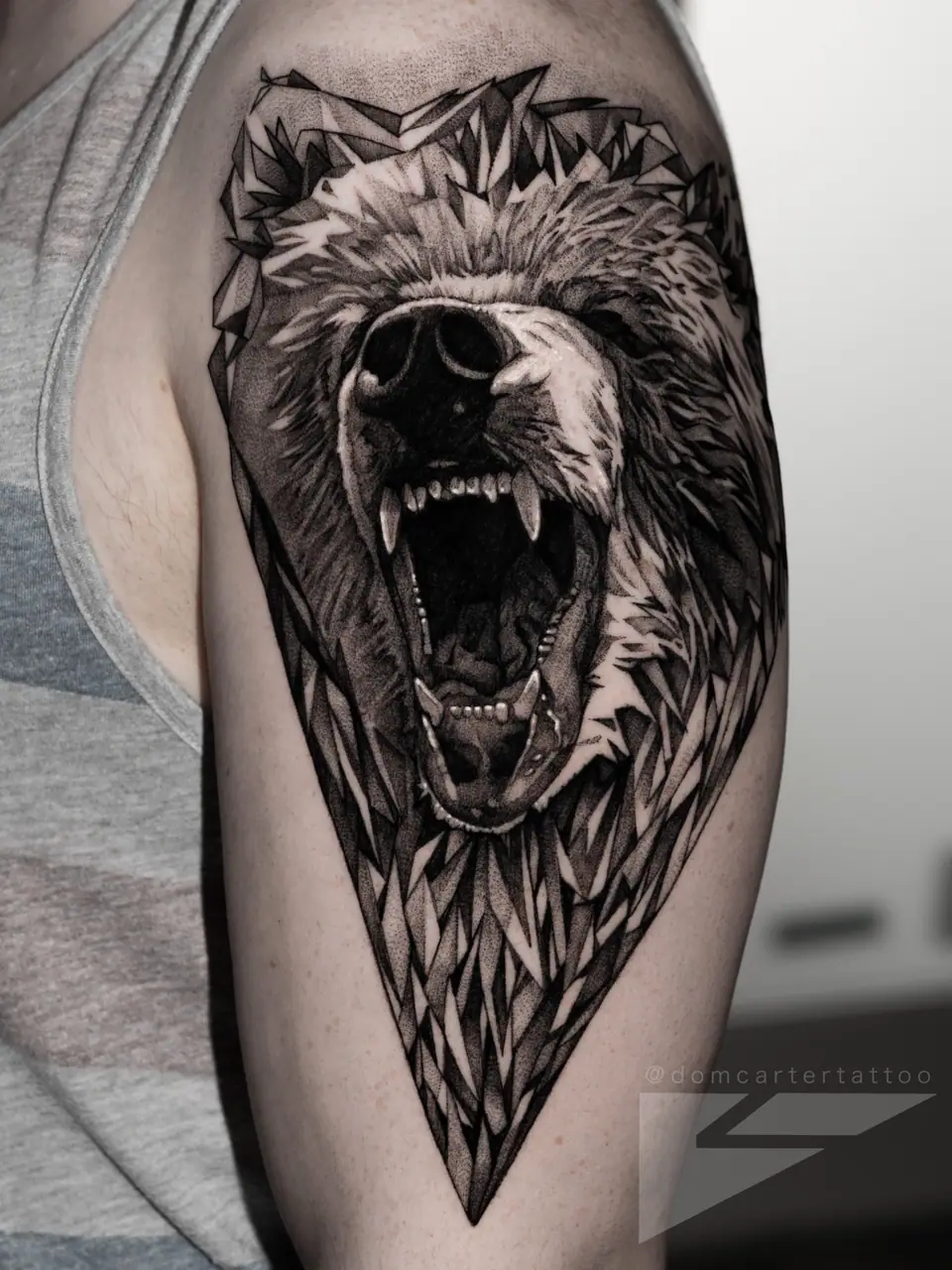 Tatuaje blackwork de una cabeza de oso rugiendo, en el brazo