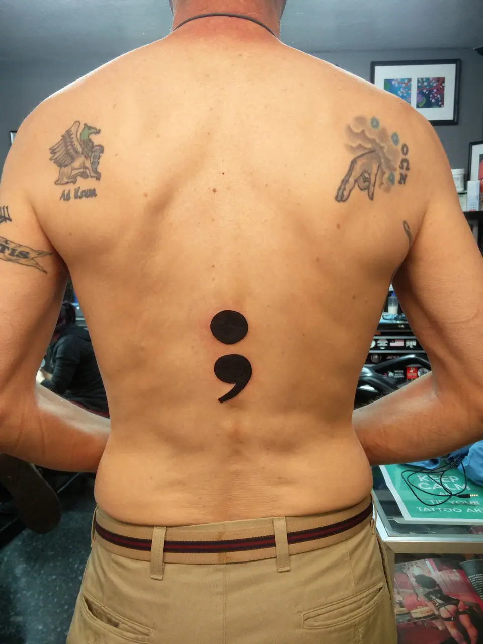 Tatuaje de un punto y coma en la espalda, entre los omóplatos