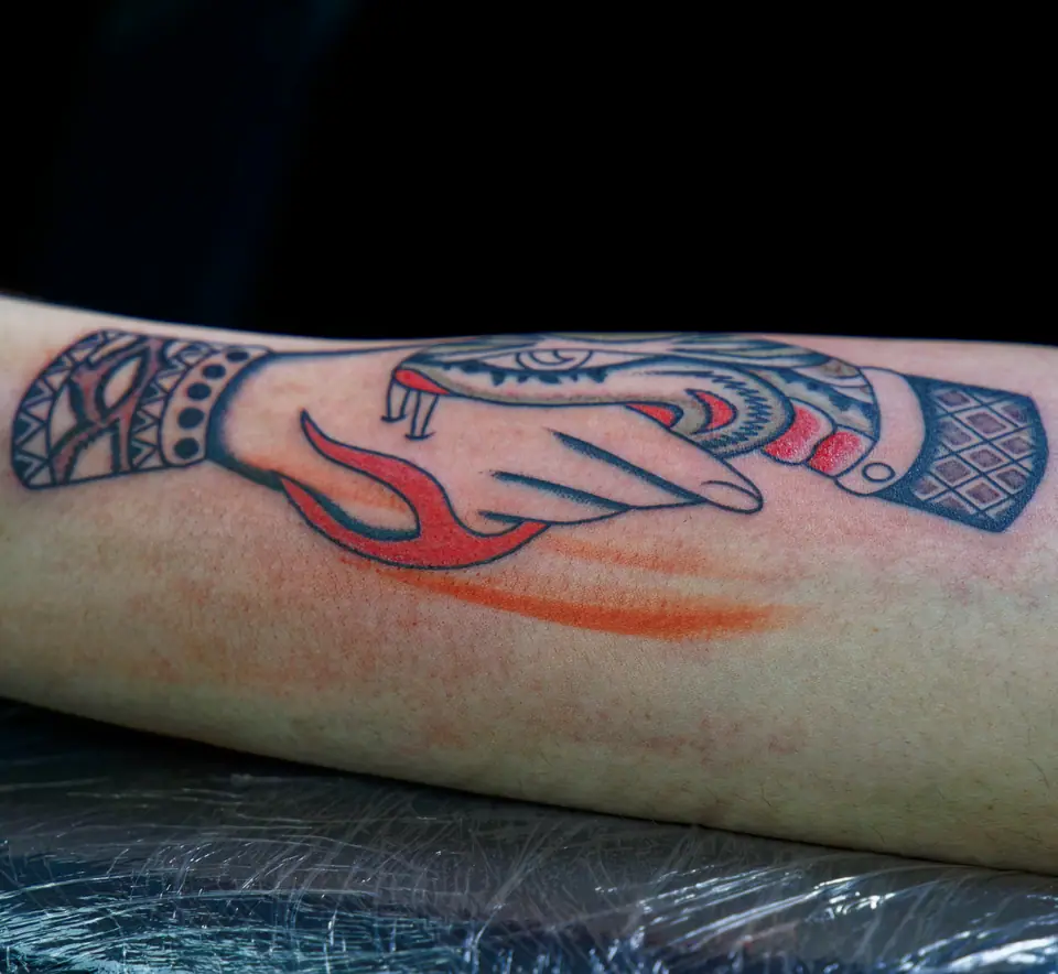 Tatuaje de una serpiente mordiendo una mano