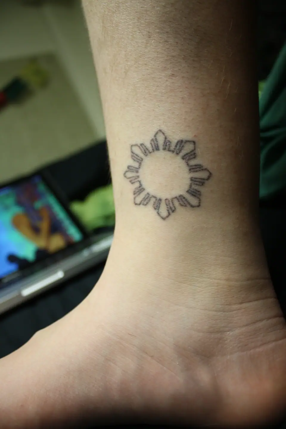 Tatuaje stick and poke de sol filipino en el tobillo