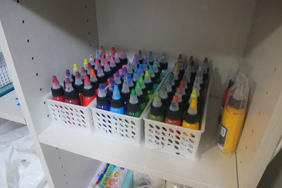 Estante con botellas de tinta de tatuaje de varios colores